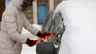 女青年在暴风雪后用刮泥机<strong>清洗汽车</strong>